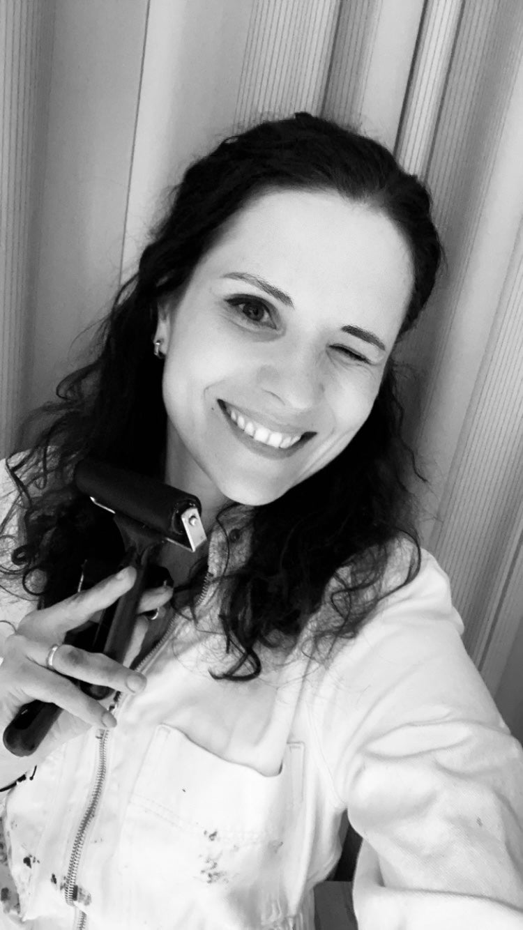 black and white photo of a smiling woman with dark curly hair, wearing a painter overall